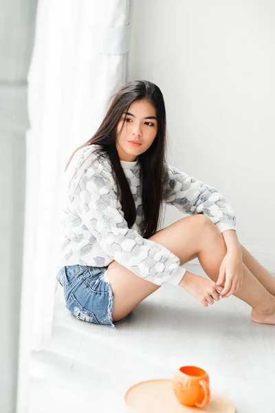 Attente Aziatische tiener zittend op de vloer in de buurt venster met Ora — Stockfoto