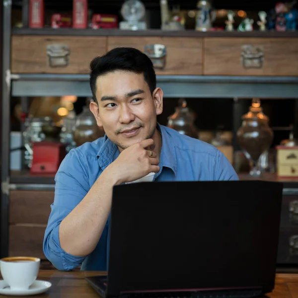 Asian man in deep thought closeup in profile with laptop.