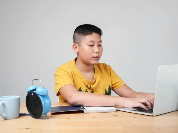 Ásia preteen menino fazendo homework com laptop com azul alarme clo — Fotografia de Stock