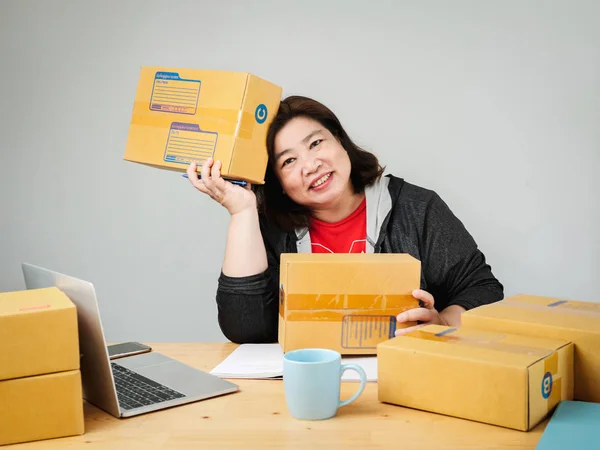 Fat Asian woman packing goods for selling online, delivery conce