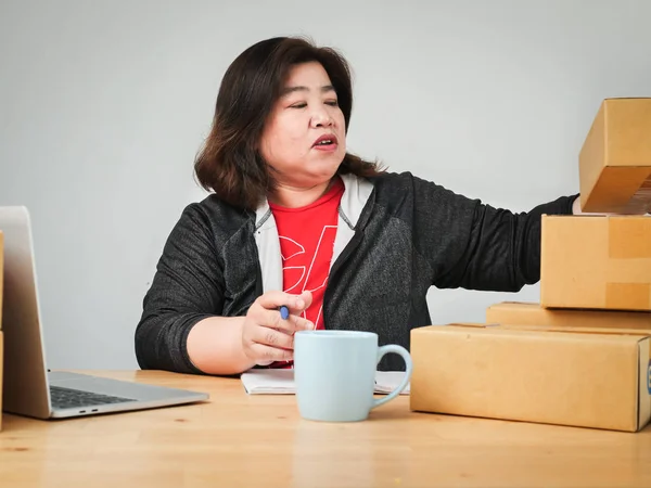 Fat Asian woman packing goods for selling online, delivery conce