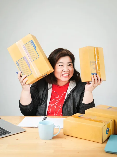 Fat Asian woman packing goods for selling online, delivery conce