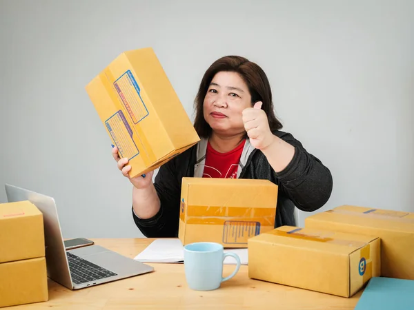 Fat Asian woman packing goods for selling online, delivery conce