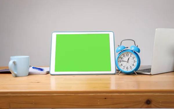 松桌上的绿色屏幕平板电脑和蓝色闹钟, 供模拟使用 — 图库照片