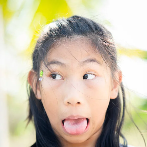 Feliz chica asiática mostrando su lengua con mocos en la nariz, vidas —  Fotos de Stock