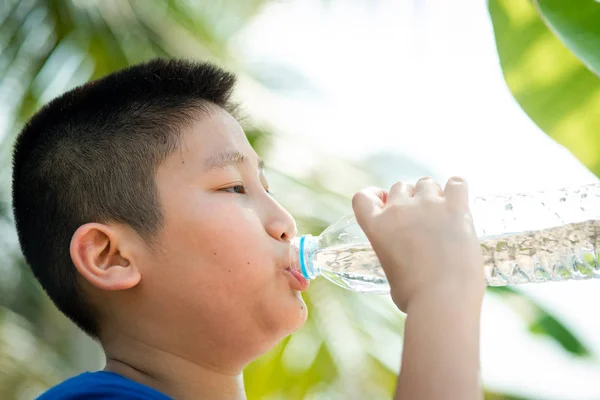 Close-up jongen is drinkwater uit plastic fles op het Park. — Stockfoto