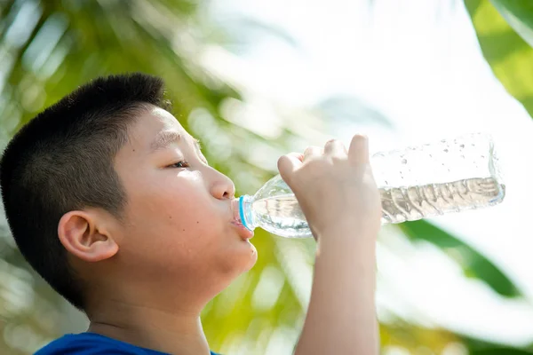 Close-up jongen is drinkwater uit plastic fles op het Park. — Stockfoto