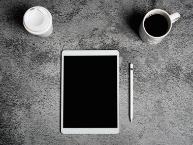 Gri çimento doku arka plan üzerinde Tablet, kalem ve kahve bardağı.