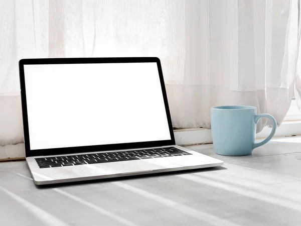 Witte scherm laptop computer, blauwe koffiemok op grijs houten tabblad — Stockfoto