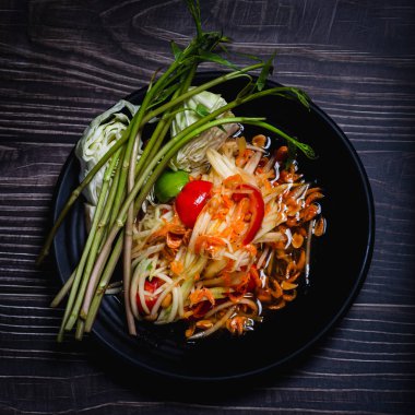 Ahşap masa arka plan ile siyah tabak üzerinde Papaya salatası.