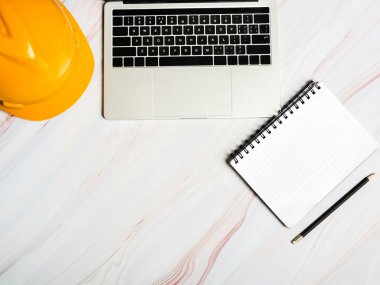 Mermer backgroun pc ve not defteri ile masada Mühendis kask