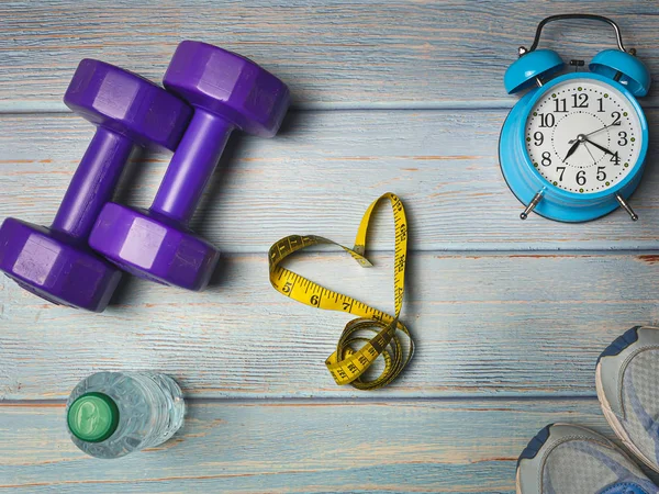 Sport shoes, blue alarm clock, bottle of water and heart shape o