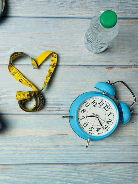 Sport shoes, blue alarm clock, bottle of water and heart shape o