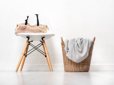 Beyaz sandalye ve ahşap flo üzerinde giysi saman sepeti kumaş çanta