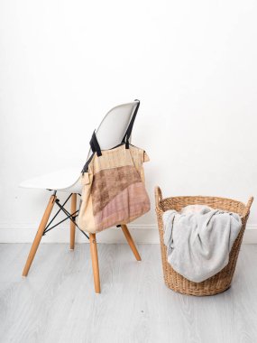 Beyaz sandalye ve ahşap flo üzerinde giysi saman sepeti kumaş çanta