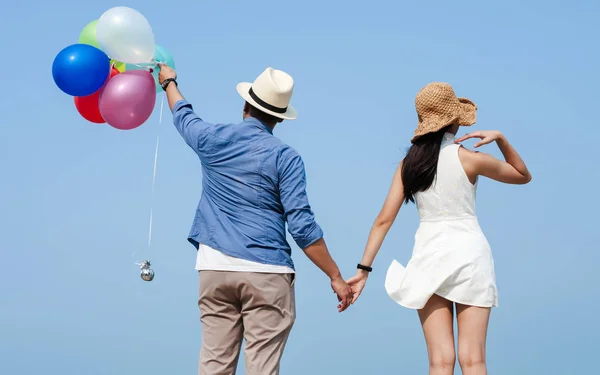Azjatycka para trzyma kolorowe balony na plaży w słoneczny dzień — Zdjęcie stockowe