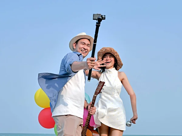 Couple asiatique prenant des photos avec des ballons sur la plage à — Photo