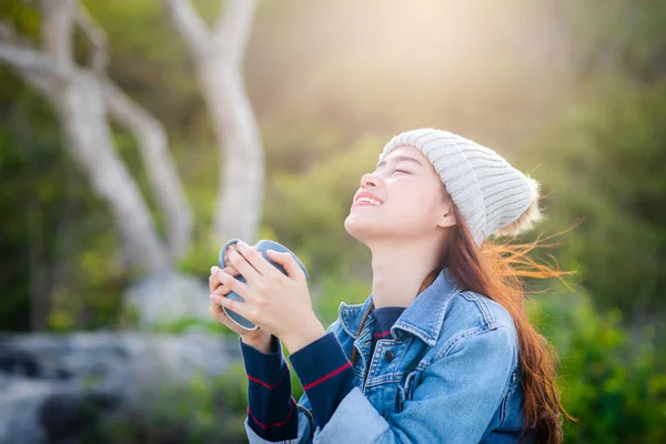 Happy Asian woman holding coffee mug with nature background, cam — Stock Photo, Image