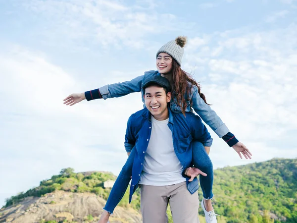 Piggy back Asian couple with blue sky and cloud, love concept.