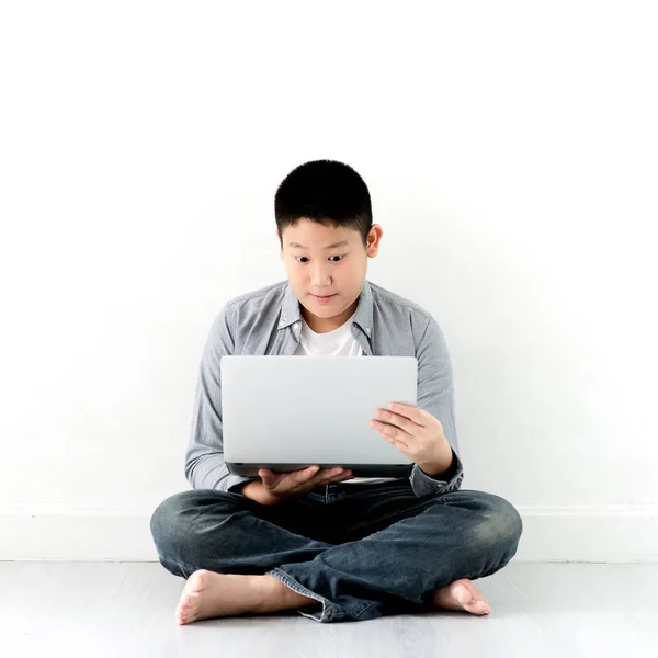 Surprising Asian preteen boy looking at laptop while sitting on — Stock Photo, Image