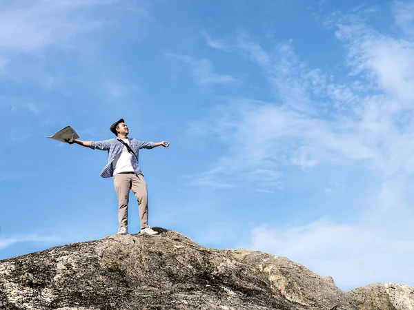 Asiatico turista in piedi sulla roccia e alzando le mani con blu s — Foto Stock