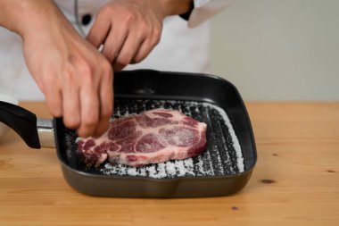 Şef yemek hazırlamak için et üzerine karabiber ve tuz yayılıyor