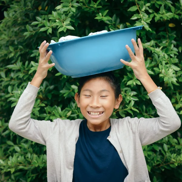 Asiatisk tjej håller blå kläder Basin med grön träd bakgrund — Stockfoto