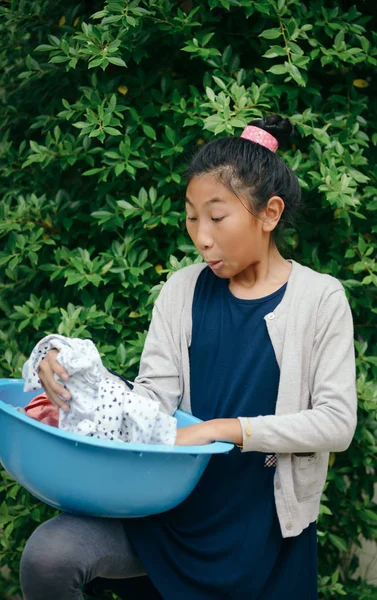 緑の木の背景を持つ青い服の洗面器を持つアジアの女の子 — ストック写真