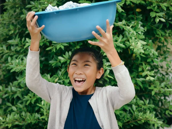 Menina asiática segurando bacia de roupas azul com fundo de árvore verde — Fotografia de Stock