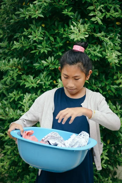 Asiatico ragazza holding blu abiti bacino con verde albero sfondo — Foto Stock