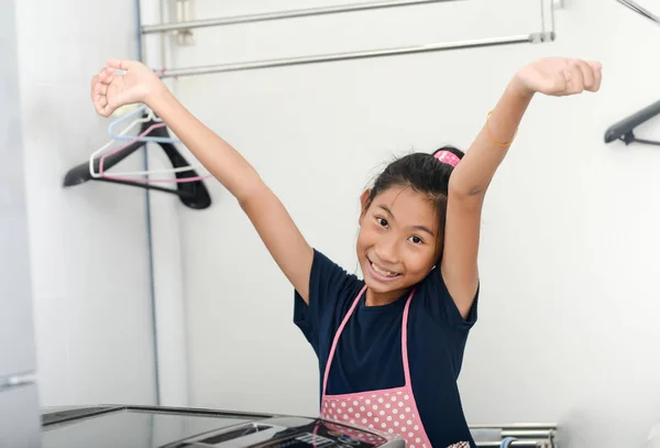 เด็กสาวเอเชีย ยกมือขึ้น หลังจากซักรีดที่บ้าน ทํางานบ้าน — ภาพถ่ายสต็อก