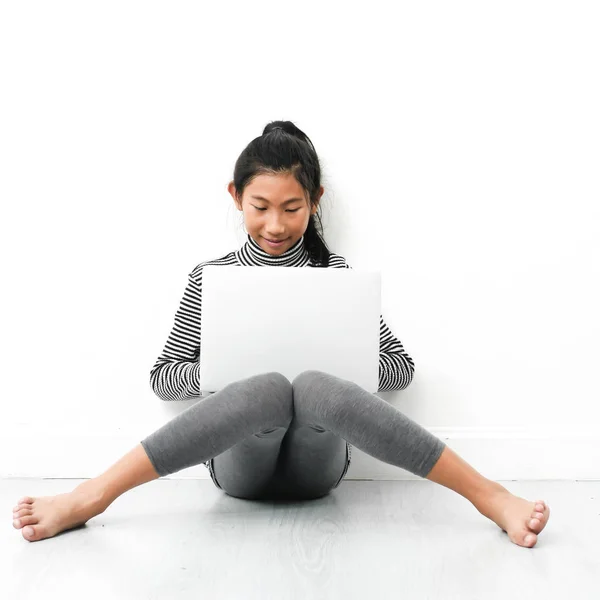 Asiatisk tjej sitter på golvet och använder laptop hemma. — Stockfoto