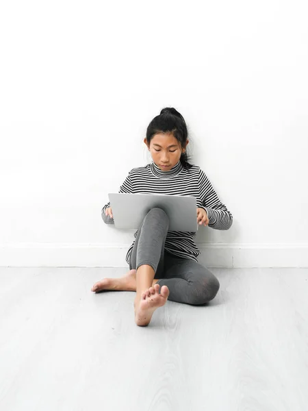 Asiatisk tjej sitter på golvet och använder laptop hemma. — Stockfoto