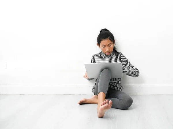 Asyalı kız katta oturan ve evde dizüstü bilgisayar kullanarak. — Stok fotoğraf