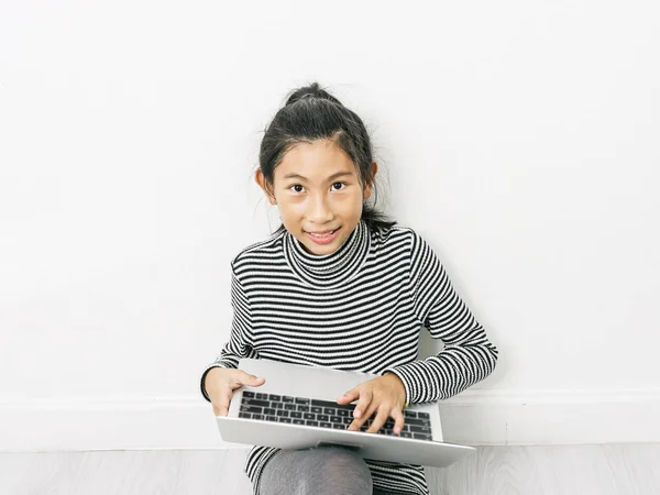 Aziatisch meisje zittend op de vloer en het gebruik van laptop thuis. — Stockfoto