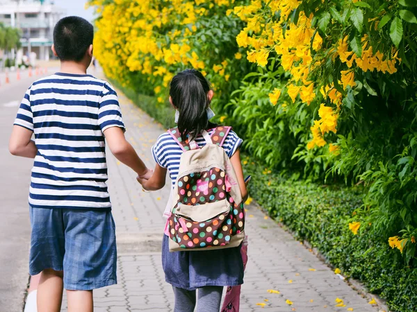 Back of brother holding his sister walking along the road with y — Stock Photo, Image