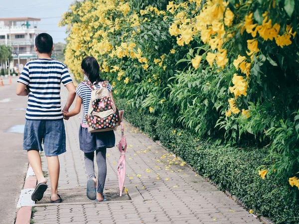 Back of brother holding his sister walking along the road with y — Stock Photo, Image