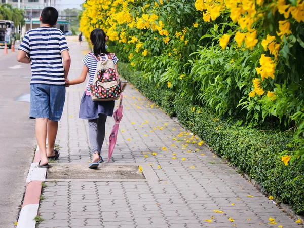 Detrás del hermano sosteniendo a su hermana caminando por el camino con y —  Fotos de Stock