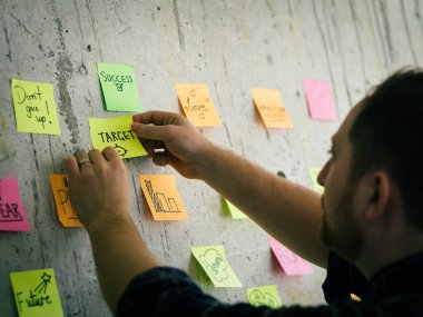 Yapışkan kağıt mesaj tutan Adam çimento duvar ile hedef yazmak.