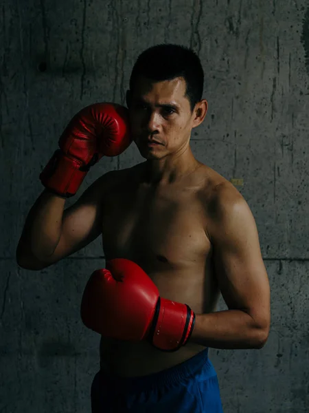 Азиатский боксер с красной перчаткой, стоящей напротив цементной стены, с низкой крышкой — стоковое фото