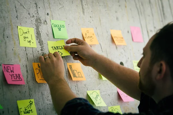 Man håller klibbigt papper meddelande skriva mål med cement Wall. — Stockfoto