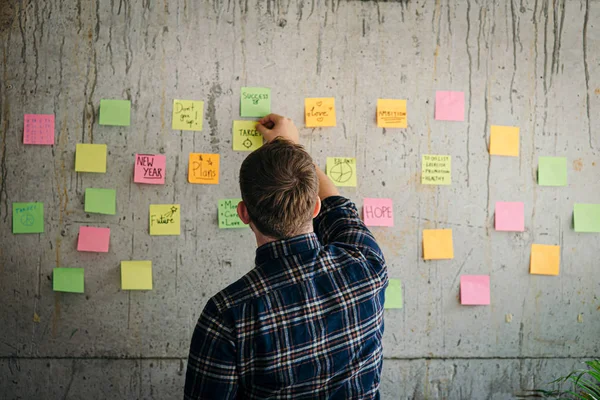 Uomo che tiene appiccicoso messaggio di carta scrivere bersaglio con muro di cemento . — Foto Stock