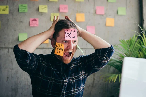Stressed man with message on sticky notes over his face in offic