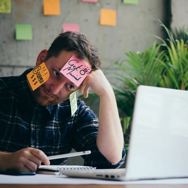 Man met bericht op plaknotities benadrukt over zijn gezicht in kantoor — Stockfoto