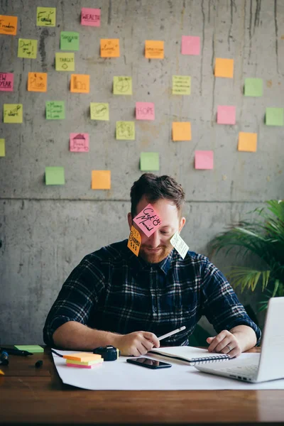 Man met bericht op plaknotities benadrukt over zijn gezicht in kantoor — Stockfoto