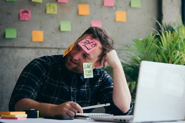 Stressed man with message on sticky notes over his face in offic — Stock Photo, Image
