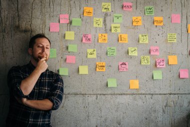 Mutlu bir adam kol yapışkan notlar grafik ile çimento duvara geçti. E