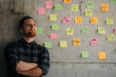 Mutlu bir adam kol yapışkan notlar grafik ile çimento duvara geçti. E