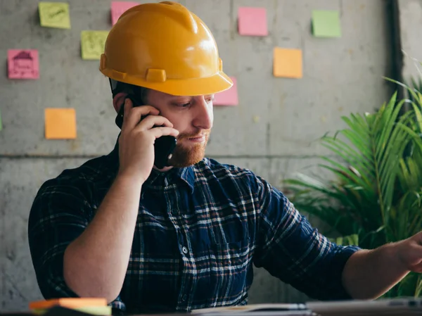Inženýr hovoří s telefonem a pitnou kávou v kanceláři, barevně — Stock fotografie
