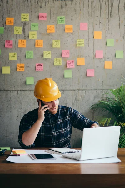 Ingenjör pratar med telefon och titta på laptop i Office, Col — Stockfoto